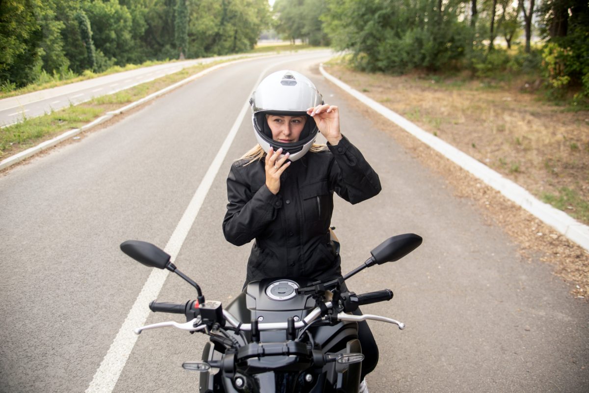 femme debout sur sa moto avec casque